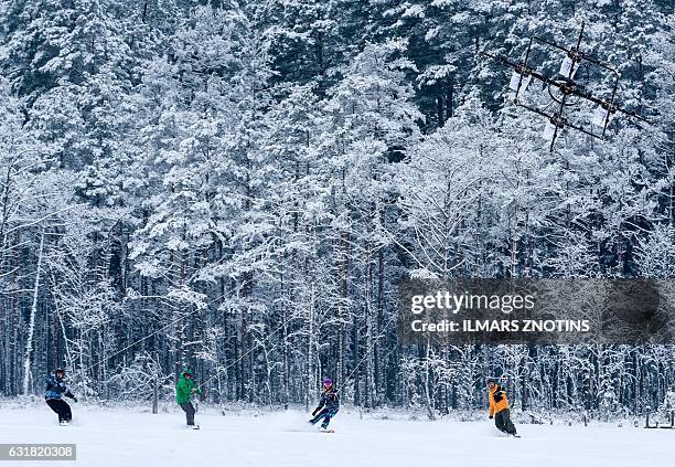 Snowboarders are pulled by sixteen propeller drone on Niniera lake surface near Cesis, Latvia, on January 14, 2017. / AFP / afp / Ilmars ZNOTINS