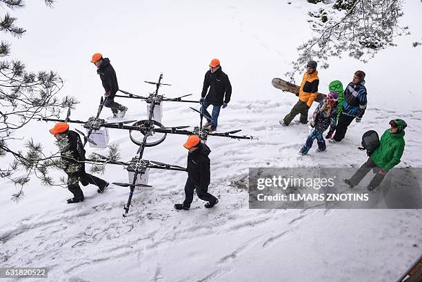 Snowboarders walk as sixteen propeller drone is carried to Niniera lake surface near Cesis, Latvia, on January 14, 2017. / AFP / afp / Ilmars ZNOTINS
