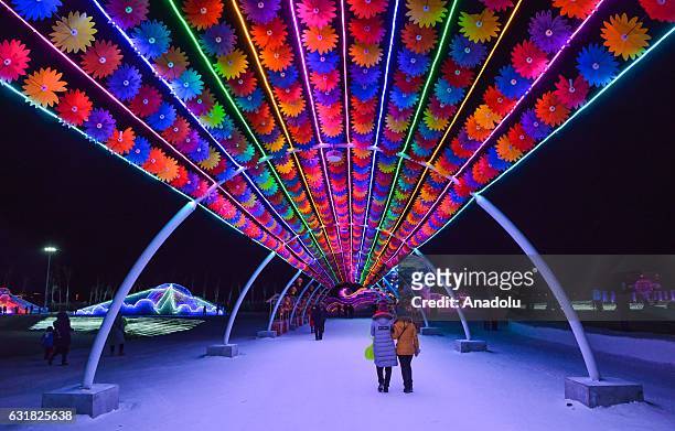 Tourists walk through an illuminated and decorated road during the 33rd Harbin International Ice and Snow Festival at Harbin Ice And Snow World in...