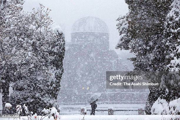 Man walks past near the A-Bomb Dome as snow falls in wider area on January 15, 2017 in Hiroshima, Japan. The Meteorological Agency is warning many...