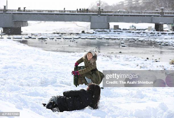 Children play with snow at a river bank of Kamogawa River as snow falls in wider area on January 15, 2017 in Kyoto, Japan. The Meteorological Agency...