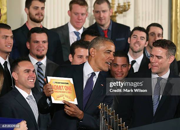 President Barack Obama shows a free pass to Wrigley Field given to him by the 2016 World Series Champion Chicago Cubs in The East Room at the White...