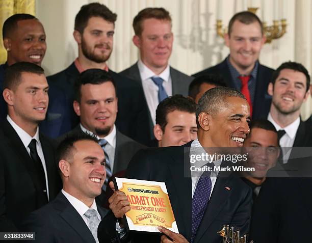 President Barack Obama shows a free pass to Wrigley Field given to him by the 2016 World Series Champion Chicago Cubs in The East Room at the White...