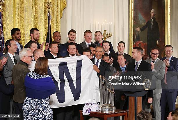 President Barack Obama shows a W flag given to him by the 2016 World Series Champion Chicago Cubs in The East Room at the White House, on January 16,...