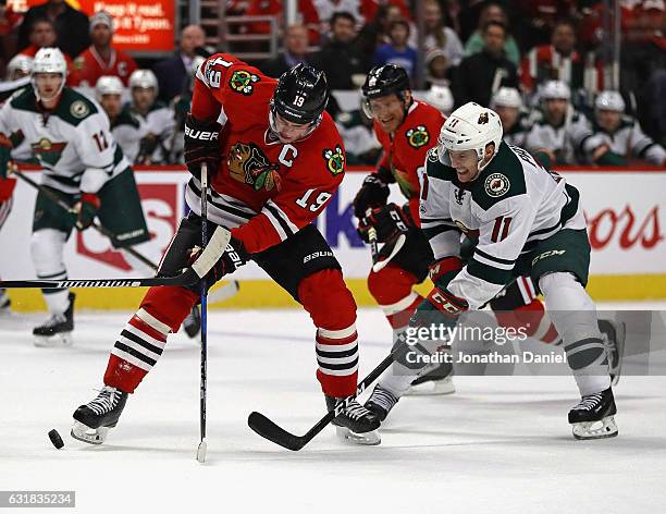 Jonathan Toews of the Chicago Blackhawks tries to control the puck under pressure from Zach Parise of the Minnesota Wild at the United Center on...