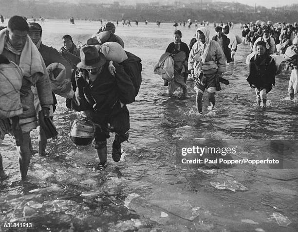 Refugees fleeing from the Chinese Communist forces wade across the Taedong River near Pyongyang in North Korea, during the Korean War, 13th December...