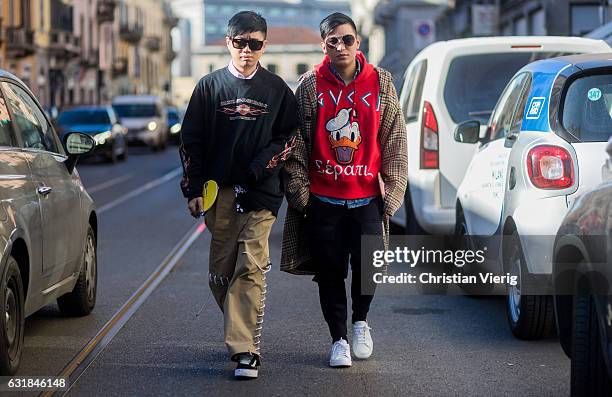 Declan Chan wearing a black sweater, brown pants, Vans and Bryan Boy wearing a Gucci Donald Duck hoody, checked coat, black pants, white sneaker at...