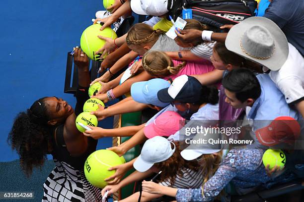 Serena Williams of the United States signs autographs for fans after winning her first round match against Belinda Bencic of Switzerland on day two...