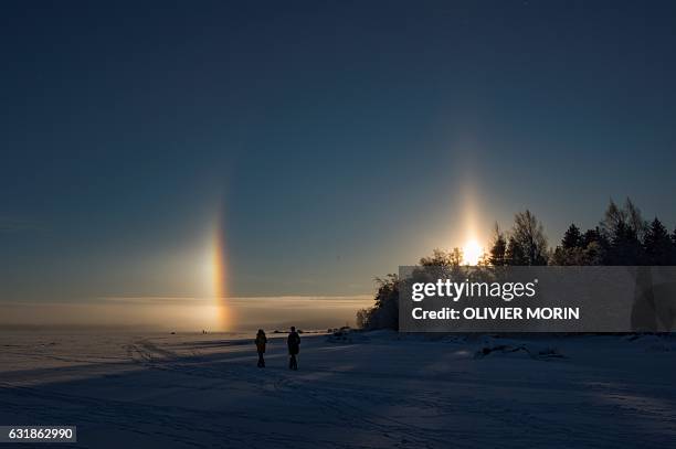 People walk near a solar halo on the frozen sea in Vaasa by -15°C, on January 15, 2017. The Halo is an optical phenomena produced by light...