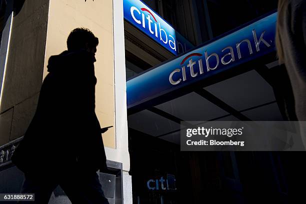 The silhouette of a pedestrian holding a mobile device is seen walking past a Citigroup Inc. Bank branch in San Francisco, California, U.S., on...