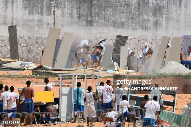 Prisoners cover themselves using makeshift shields as riot police agents fire rubber bullets during a rebellion at the Alcacuz Penitentiary Center...