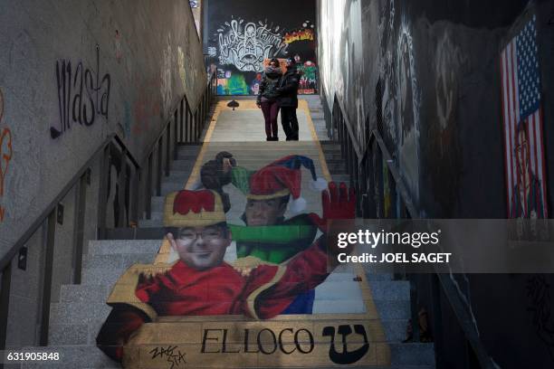 French street art duo Zag and Sia pose in front of one of their works on a stairway in Paris on January 17, 2017. The work features a portrait of...