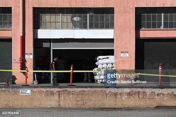 Security guard stands at an entrance to an American Apparel factory on January 17, 2017 in Los Angeles, California. American Apparel has begun laying...