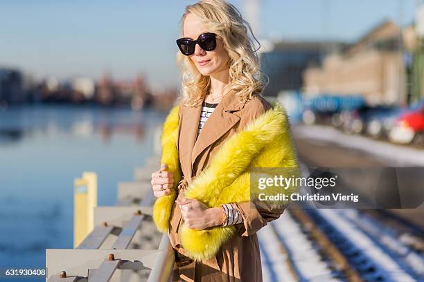 Kathrin Gelinsky wearing a brown Marc Cain trench coat, yellow fur scarf, sunglasses, striped top Marc Cain during the Mercedes-Benz Fashion Week...