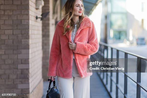 Sandra Kleine Staarman wearing a salmon pink Marc Cain faux fur jacket, white wide leg Marc Cain pants, and Marc Cain blouse with bow tie, black Marc...