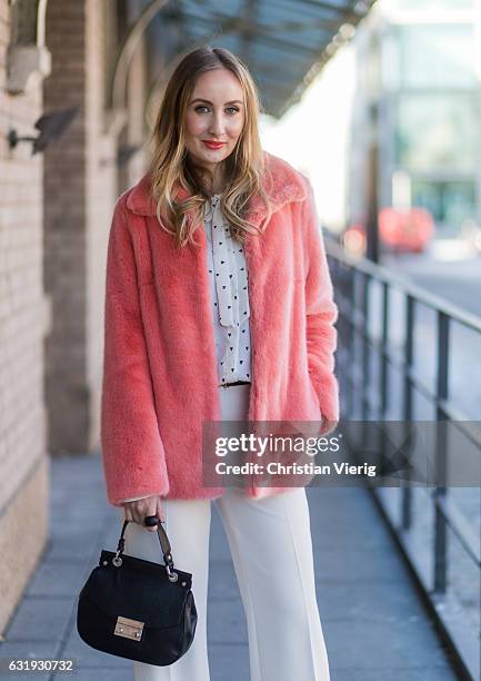 Sandra Kleine Staarman wearing a salmon pink Marc Cain faux fur jacket, white wide leg Marc Cain pants, and Marc Cain blouse with bow tie, black Marc...