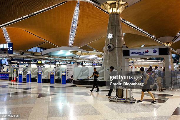 Passengers walk through the check-in hall at Kuala Lumpur International Airport in Sepang, Selangor, Malaysia, on Tuesday, Jan. 17, 2017. The hunt...