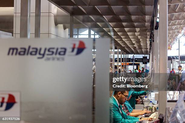 Malaysian Airlines Bhd. Ground staff work at check-in counters at Kuala Lumpur International Airport in Sepang, Selangor, Malaysia, on Tuesday, Jan....