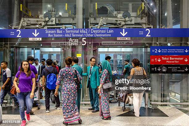 Passengers and Malaysian Airlines Bhd. Ground staff enter and exit elevators in the check-in hall at Kuala Lumpur International Airport in Sepang,...