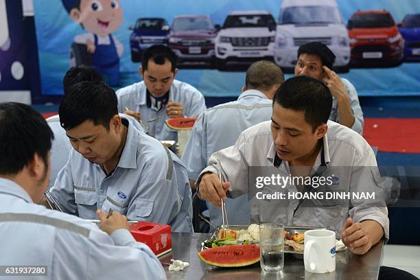 This picture taken on January 11, 2017 shows Vietnamese employees eating lunch at the Ford automotive plant in the northern province of Hai Duong....