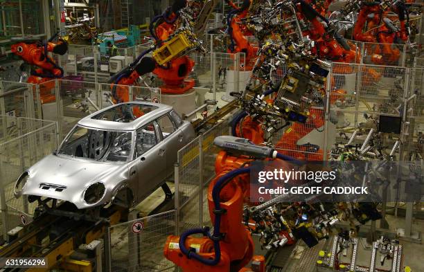 Minis in the 'Body in white' stage of manufacture pass along a robotic assembly line at the BMW Mini car production plant in Oxford, west of London,...