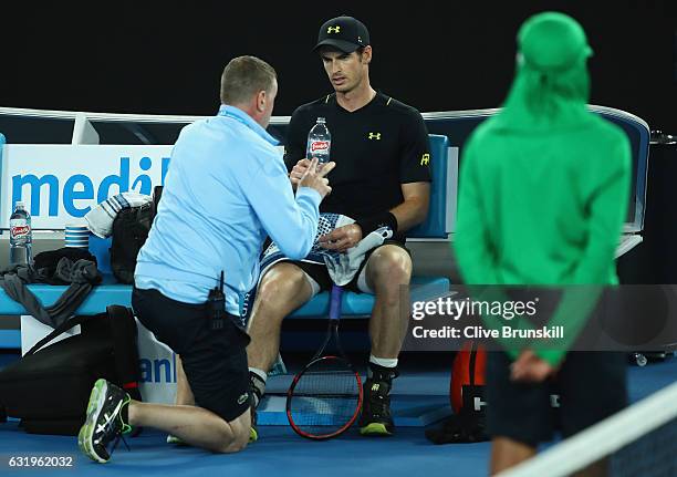 Andy Murray of Great Britain speaks with the physio at the change of ends after injuring his ankle after he fell over in his second round match...