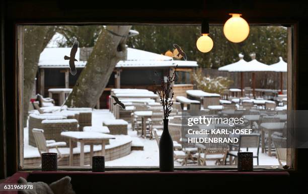 View taken from a restaurant's window shows tables and chairs of a beer garden covered in snow on January 18, 2017 near Inning am Ammersee, southern...