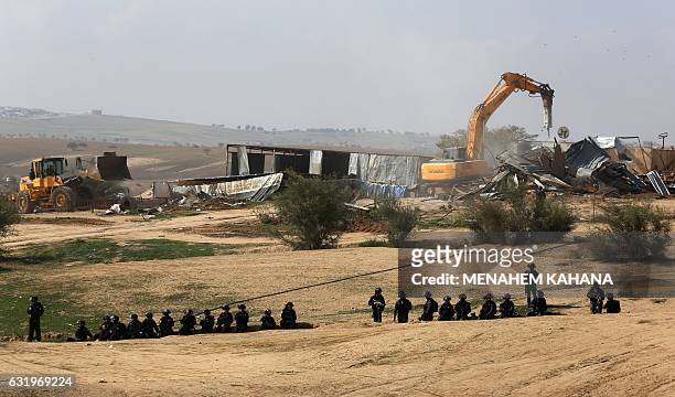 Israeli policemen stand guard as bulldozers demolish homes in the Bedouin village of Umm al-Hiran, which is not recognized by the Israeli government,...