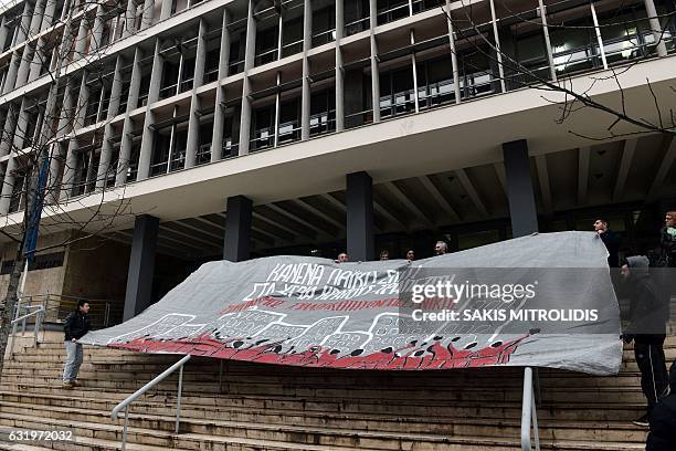 Demonstrators hold a banner reading "No laic home in the hands of state-bankers" as they protest against real estate auctions outside of the...