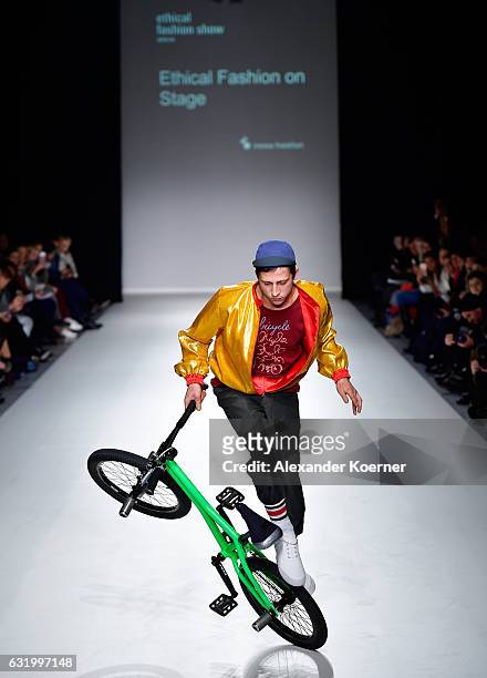 Cyclist model rides a bicycle on the runway at the Ethical Fashion show during the Mercedes-Benz Fashion Week Berlin A/W 2017 at Postbahnhof on...