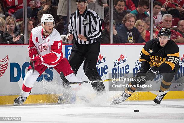 Justin Abdelkader of the Detroit Red Wings races for the puck with Brandon Carlo of the Boston Bruins during an NHL game at Joe Louis Arena on...