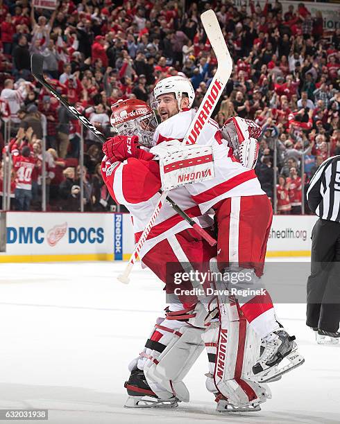 Tomas Tatar of the Detroit Red Wings jumps into the arms of teammate goaltender Petr Mrazek of the Detroit Red Wings following their shoot-out win of...