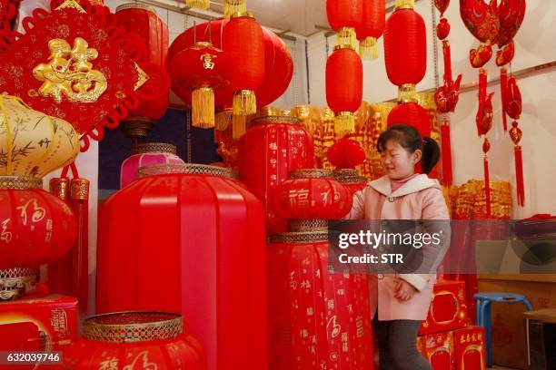 This photo taken on January 18, 2017 shows a Chinese girl playing among lanterns and decorations at a shop ahead of the Lunar New Year in Xian, in...