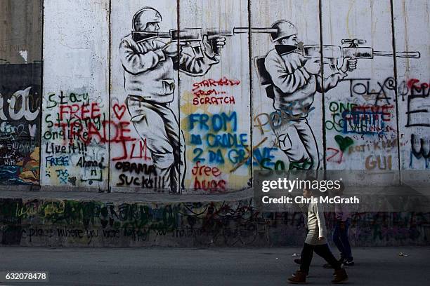 Children walk past graffiti painted on the Palestinian side of the separation wall on January 18, 2017 in Bethlehem, West Bank. 70 countries attended...