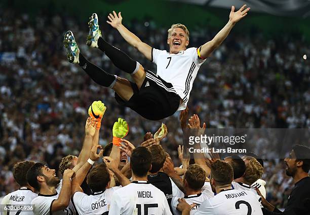 Bastian Schweinsteiger of Germany is thrown in to the air by team mates after his last international match during the International Friendly match...