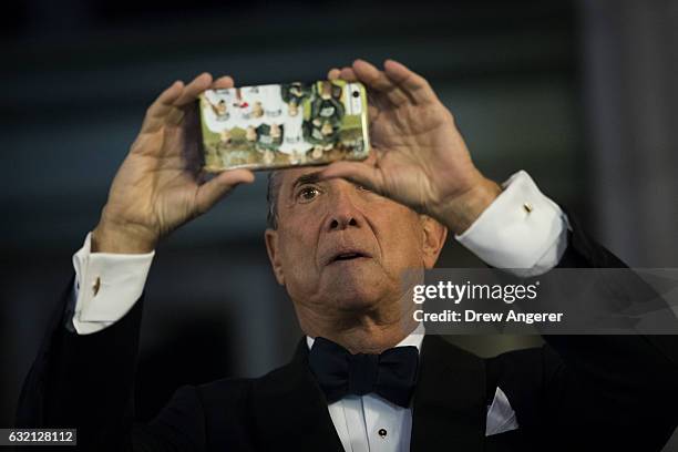 Lewis 'Lew' Eisenberg takes a photo as he arrives at Union Station for a dinner for Trump campaign donors, January 19, 2017 in Washington. DC....