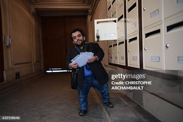 President of the French Association of Small People Othmane El Jamali takes out his mail from his box at his home in Paris on January 6, 2017. Words...