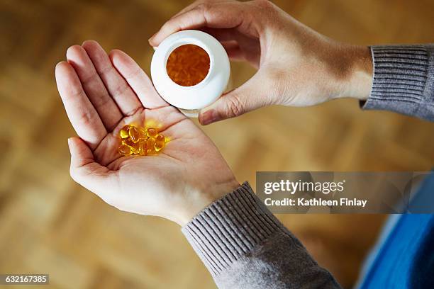 young woman taking medication from bottle, close-up - complément vitaminé photos et images de collection