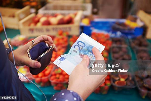 young woman at market, taking money from purse, mid section - münzbeutel stock-fotos und bilder