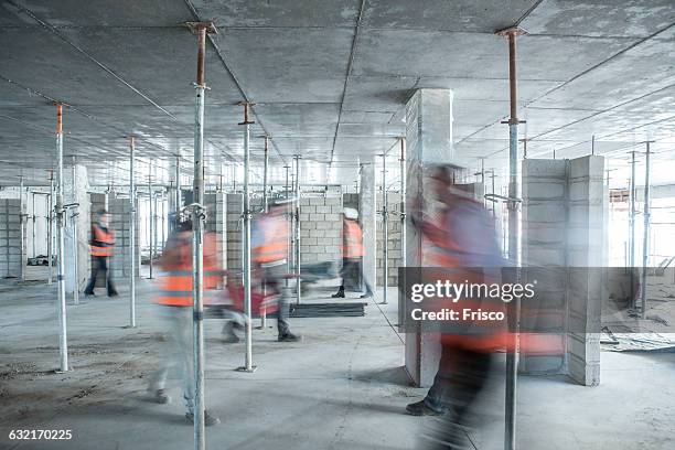 six blurred construction workers on the go in busy construction site - baustelle stock-fotos und bilder