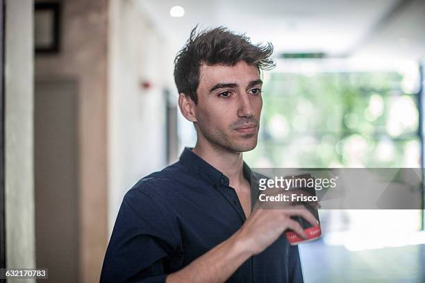 serious young businessman drinking takeaway coffee in office - delusione foto e immagini stock