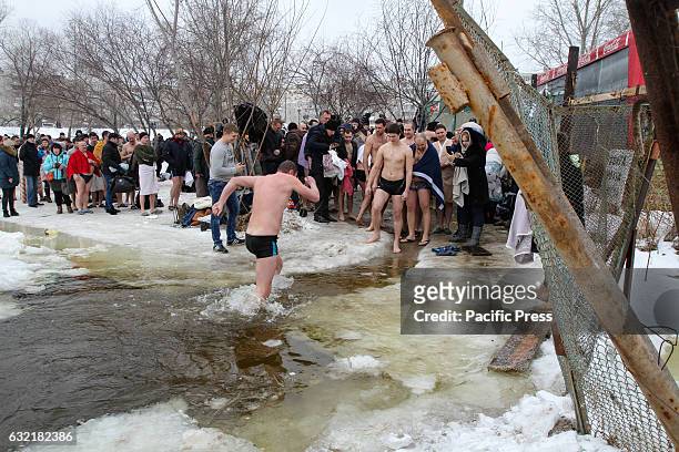 Ukrainian Orthodox believers bathe in cross-alike ice-holes on Dnipro river as they celebrate Epiphany.