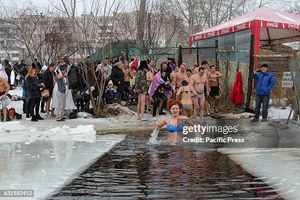 Ukrainian Orthodox believers bathe in cross-alike ice-holes on Dnipro river as they celebrate Epiphany.