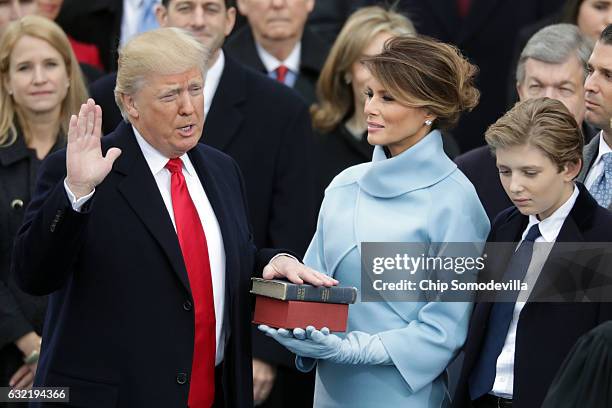 President Donald Trump takes the oath of office as his wife Melania Trump holds the bible and his son Barron Trump looks on, on the West Front of the...