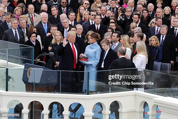 Supreme Court Justice John Roberts administers the oath of office to U.S. President Donald Trump as his wife Melania Trump holds the Bible and his...