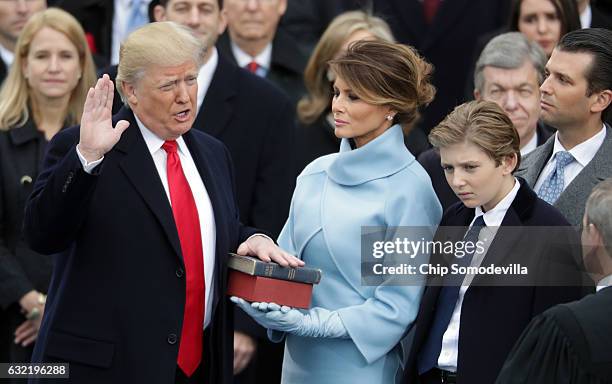 President Donald Trump takes the oath of office as his wife Melania Trump holds the bible and his son Barron Trump looks on, on the West Front of the...