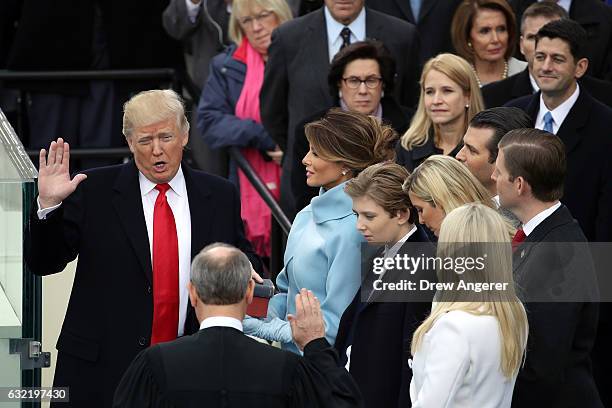 Supreme Court Justice John Roberts administers the oath of office to U.S. President Donald Trump as his wife Melania Trump holds the Bible on the...