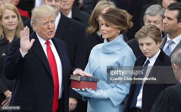 President Donald Trump takes the oath of office as his wife Melania Trump holds the bible and his son Barron Trump looks on, on the West Front of the...