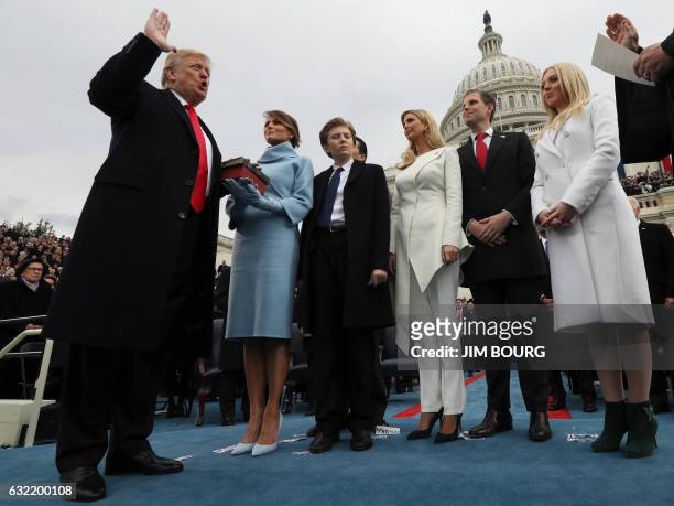 President Donald Trump takes the oath of office as his wife Melania holds the bible and his children Barron, Ivanka, Eric and Tiffany watch as US...