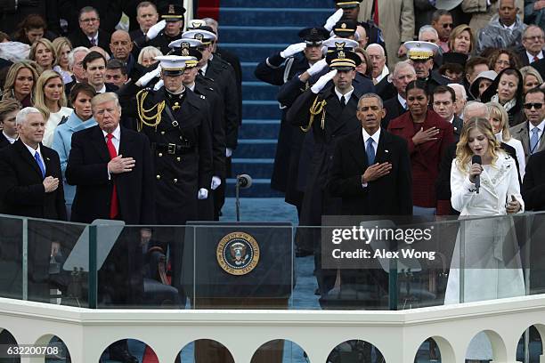 President Donald Trump and former president Barack Obama place their hands on their hearts as Jackie Evanch sings the national anthem on the West...